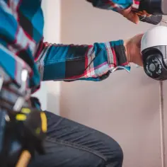 Instalacja kamery monitoringu zewnętrznego przez technika w kratę.