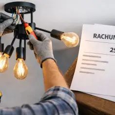 Elektryk montuje lampę, obok rachunek na 250 zł.