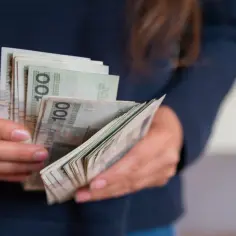 Dłonie trzymające stos banknotów 100 zł.