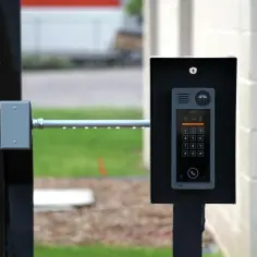 Nowoczesny domofon z klawiaturą numeryczną i kamerą na czarnym stelażu.